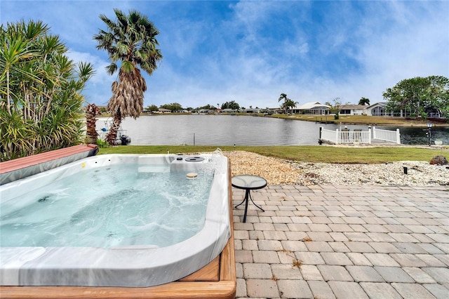 view of pool with a patio area, a lawn, a hot tub, and a water view