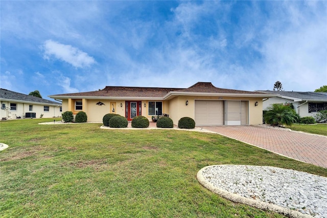 single story home featuring a front yard, decorative driveway, a garage, and stucco siding