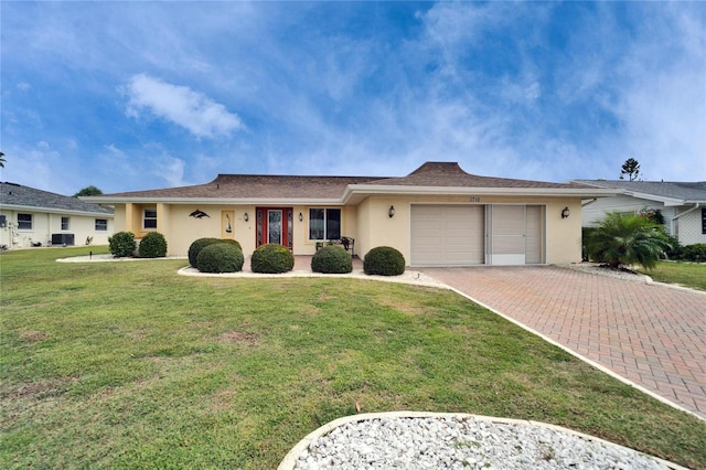 single story home featuring stucco siding, central air condition unit, a front lawn, decorative driveway, and an attached garage