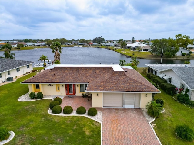 view of front of property with a front lawn, a water view, stucco siding, decorative driveway, and an attached garage