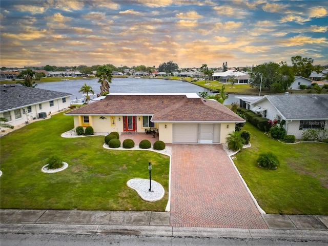 ranch-style home with stucco siding, a lawn, decorative driveway, a residential view, and an attached garage