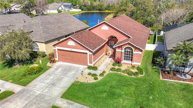 view of front of property featuring stucco siding, a water view, driveway, roof with shingles, and a garage