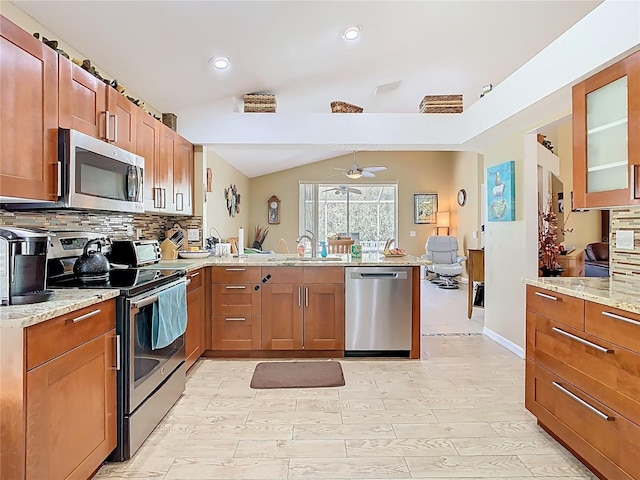 kitchen featuring decorative backsplash, a peninsula, stainless steel appliances, and a sink