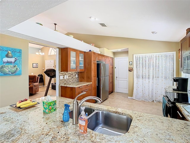 kitchen with brown cabinetry, visible vents, stainless steel appliances, and a sink