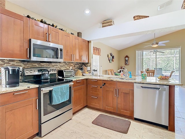 kitchen with a healthy amount of sunlight, a peninsula, a sink, vaulted ceiling, and appliances with stainless steel finishes