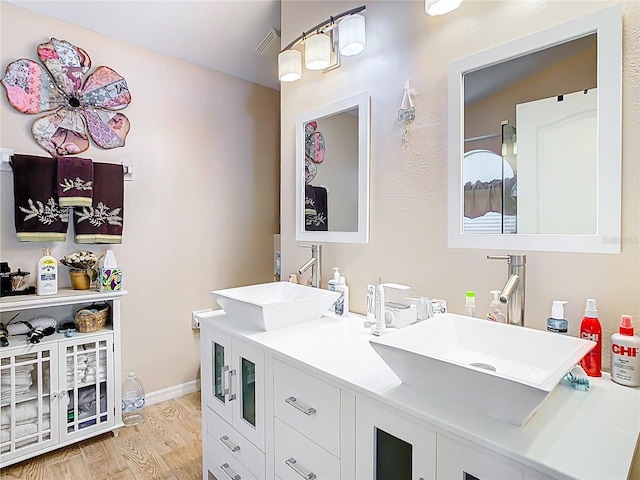 bathroom featuring double vanity, wood finished floors, visible vents, and a sink