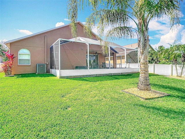 back of property featuring stucco siding, central air condition unit, and a lawn