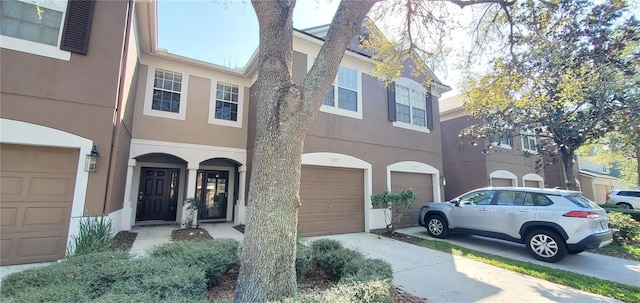 view of property with a garage, driveway, and stucco siding