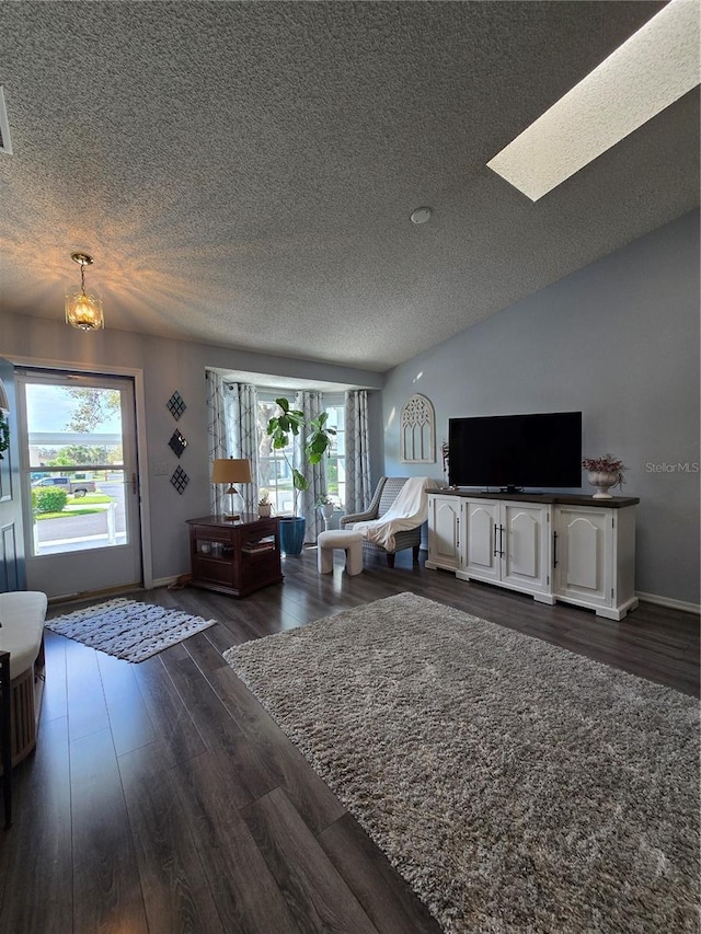 living area featuring a textured ceiling, vaulted ceiling with skylight, dark wood-style floors, and a healthy amount of sunlight