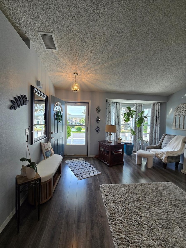 entryway with a wealth of natural light, visible vents, a textured ceiling, and hardwood / wood-style flooring