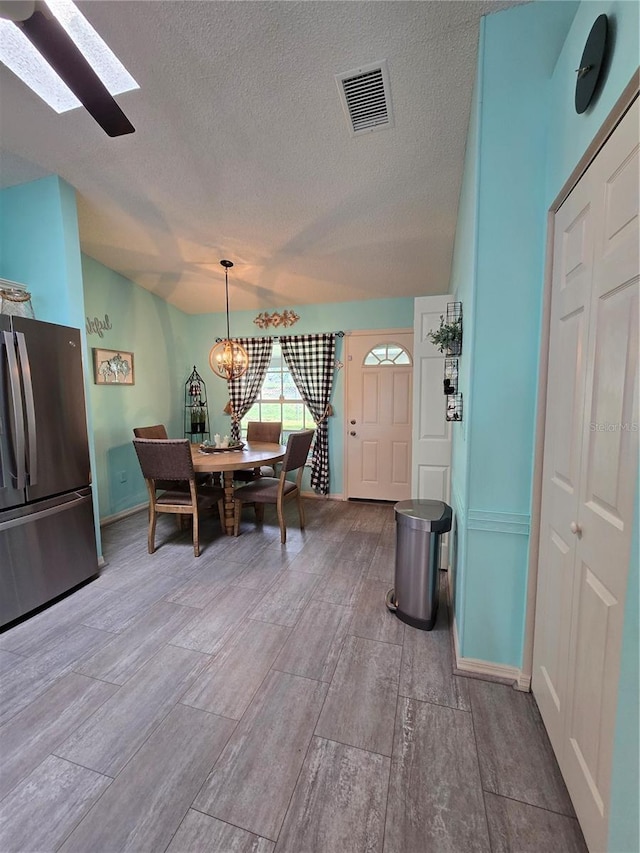 dining area with baseboards, visible vents, an inviting chandelier, a skylight, and a textured ceiling