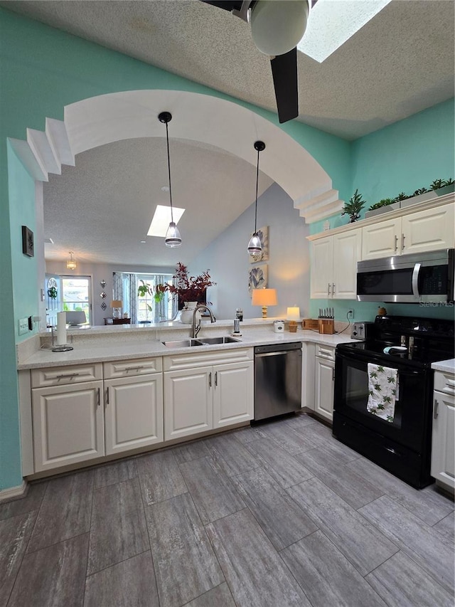 kitchen featuring light countertops, appliances with stainless steel finishes, hanging light fixtures, white cabinetry, and a sink