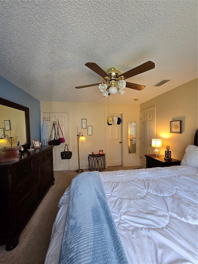 carpeted bedroom featuring visible vents, a textured ceiling, and ceiling fan