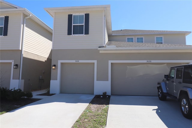 view of front of property with concrete driveway, roof with shingles, and stucco siding