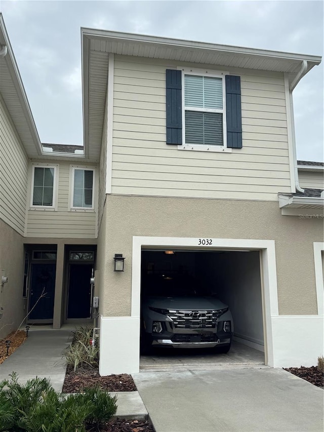 view of front facade with an attached garage, driveway, and stucco siding