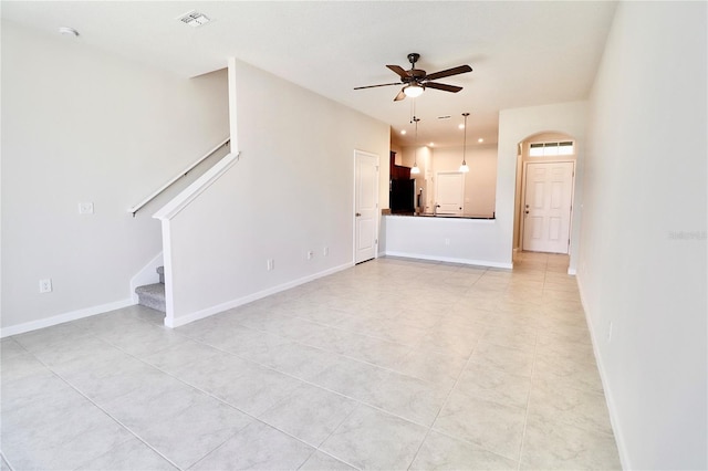 unfurnished living room featuring visible vents, stairway, baseboards, and a ceiling fan