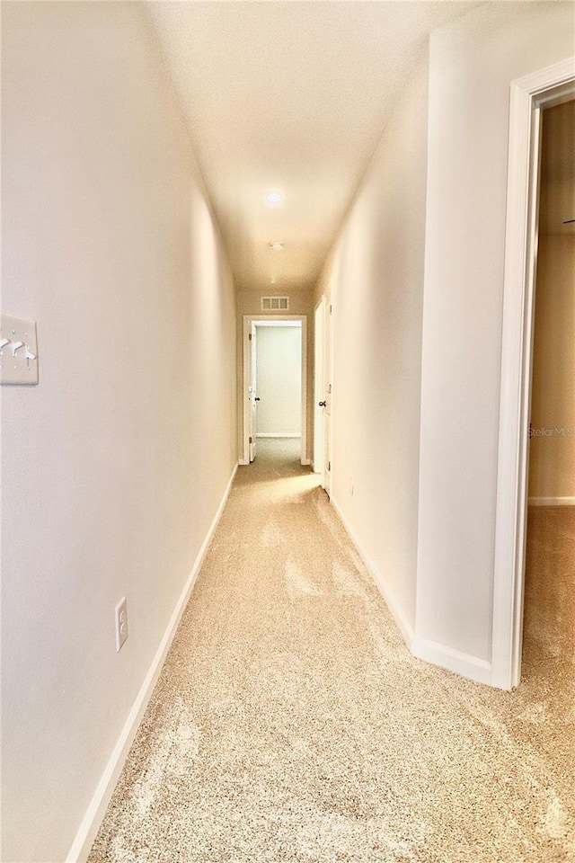 hallway featuring carpet, visible vents, and baseboards