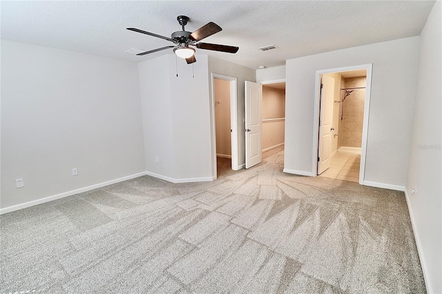 unfurnished bedroom featuring visible vents, a walk in closet, baseboards, carpet flooring, and a textured ceiling