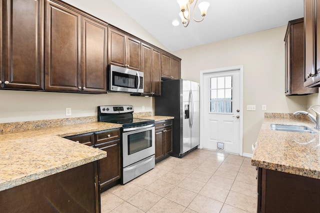 kitchen featuring light tile patterned floors, lofted ceiling, a sink, dark brown cabinetry, and appliances with stainless steel finishes