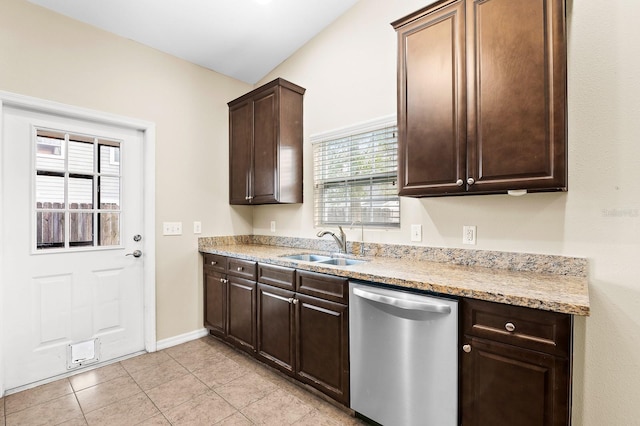 kitchen featuring dark brown cabinets, light tile patterned floors, light stone counters, stainless steel dishwasher, and a sink