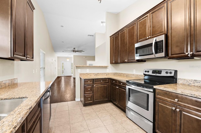 kitchen featuring dark brown cabinetry, light stone counters, appliances with stainless steel finishes, and ceiling fan