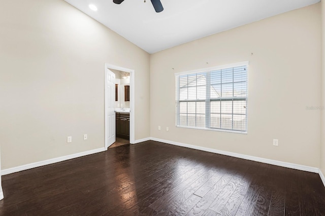 spare room featuring dark wood finished floors, a ceiling fan, baseboards, and vaulted ceiling