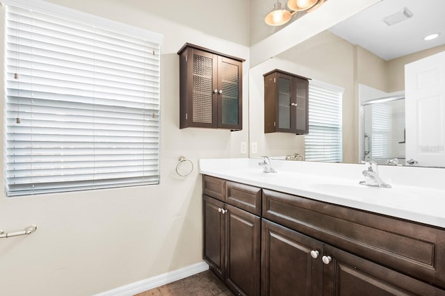 bathroom featuring a sink, baseboards, double vanity, and a shower stall