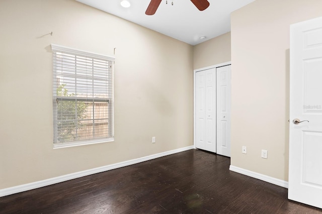 unfurnished bedroom featuring wood finished floors, baseboards, a closet, and ceiling fan