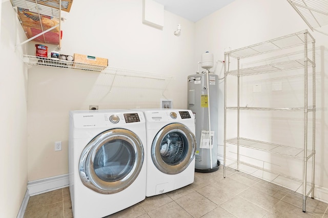 washroom with light tile patterned floors, baseboards, laundry area, electric water heater, and washer and clothes dryer