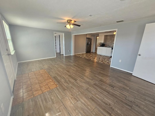 empty room featuring dark wood finished floors, visible vents, baseboards, and ceiling fan