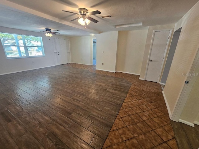 empty room with visible vents, baseboards, ceiling fan, dark wood finished floors, and a textured ceiling