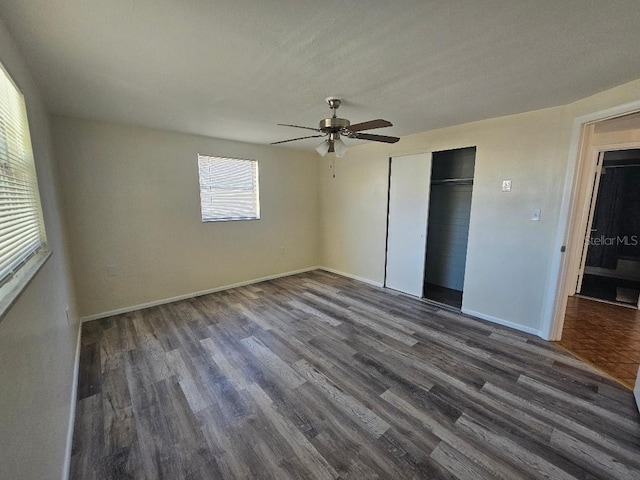 unfurnished bedroom featuring ceiling fan, a closet, baseboards, and dark wood-style floors