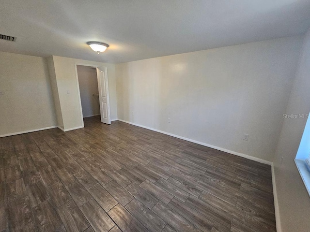 unfurnished room featuring visible vents, baseboards, and dark wood-style floors