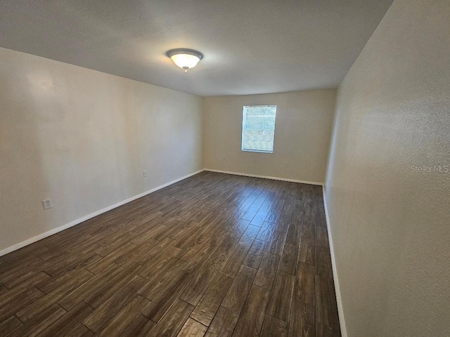 spare room featuring dark wood finished floors and baseboards