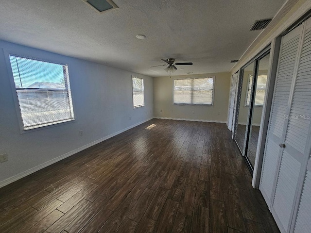 empty room featuring dark wood finished floors, baseboards, a textured ceiling, and a ceiling fan