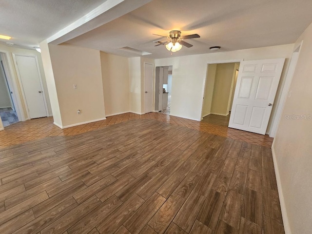 unfurnished room featuring baseboards, a ceiling fan, and dark wood-style flooring