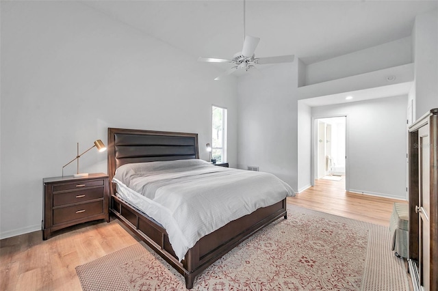 bedroom with a ceiling fan, light wood-type flooring, baseboards, and vaulted ceiling