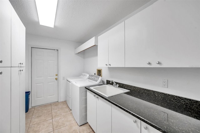 laundry room featuring light tile patterned floors, cabinet space, a textured ceiling, independent washer and dryer, and a sink