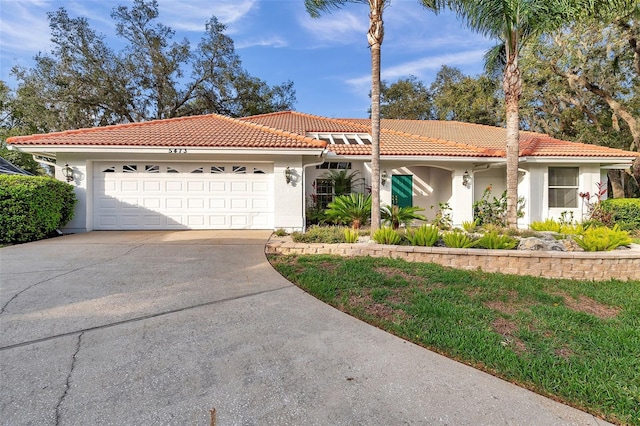 mediterranean / spanish-style home with a tile roof, an attached garage, driveway, and stucco siding