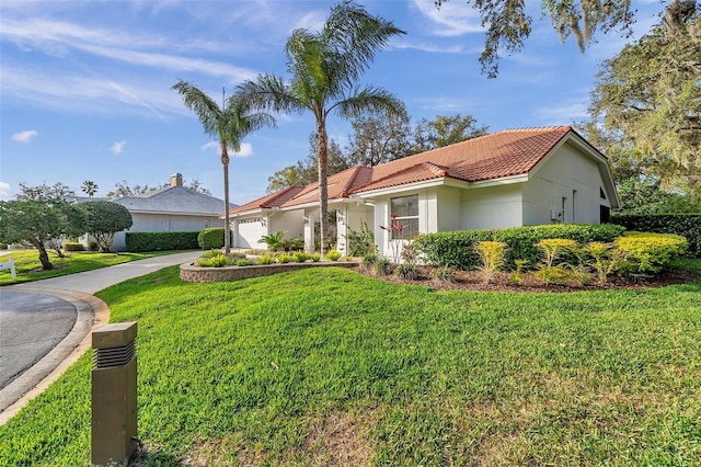 mediterranean / spanish home featuring stucco siding, driveway, a tile roof, a front yard, and a garage