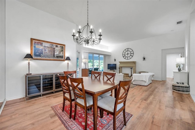 dining space featuring a notable chandelier, baseboards, visible vents, and light wood finished floors