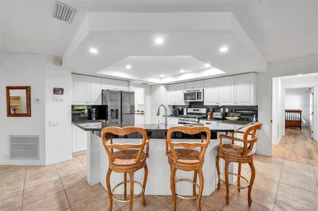 kitchen featuring a raised ceiling, dark countertops, visible vents, and stainless steel appliances