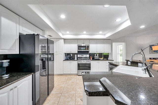 kitchen with a sink, stainless steel appliances, a raised ceiling, and light tile patterned flooring