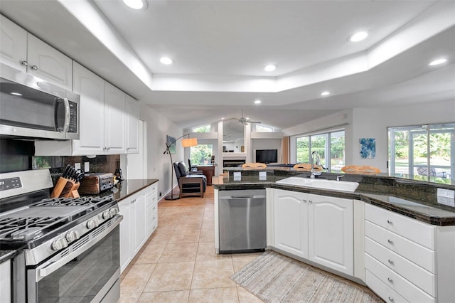 kitchen with light tile patterned floors, a tray ceiling, recessed lighting, a sink, and stainless steel appliances