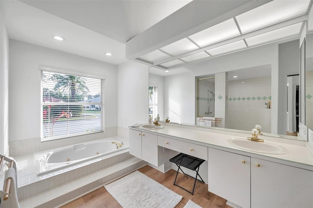 full bath with a sink, tiled shower, wood finished floors, and a whirlpool tub