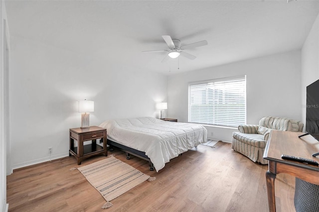 bedroom with a ceiling fan, wood finished floors, and baseboards