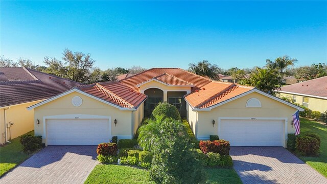 mediterranean / spanish house with stucco siding, a tile roof, decorative driveway, and a garage