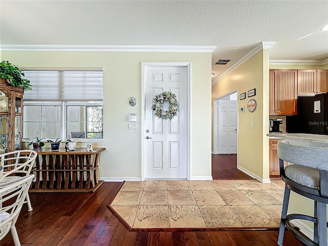 entryway with visible vents, light wood-style flooring, baseboards, and ornamental molding