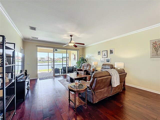 living room featuring visible vents, baseboards, dark wood finished floors, and crown molding