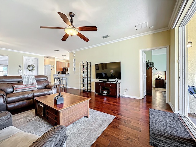 living area with visible vents, wood-type flooring, baseboards, and ornamental molding